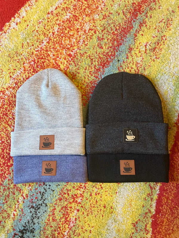Three beanies in beige, blue, and black with brand logos on a colorful textured background

