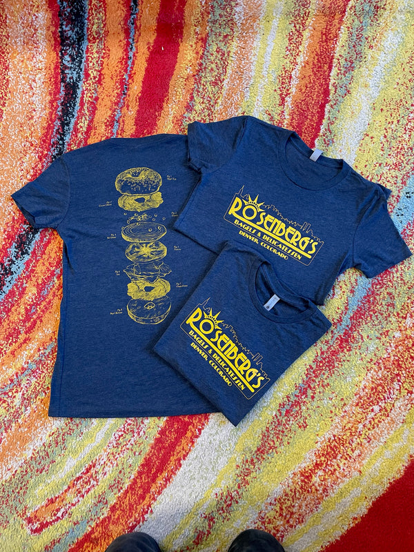 Blue t-shirt with yellow graphic and text on a colorful patterned surface