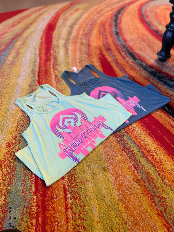 Two tank tops, one green and one gray with pink graphics, on a colorful textured surface.